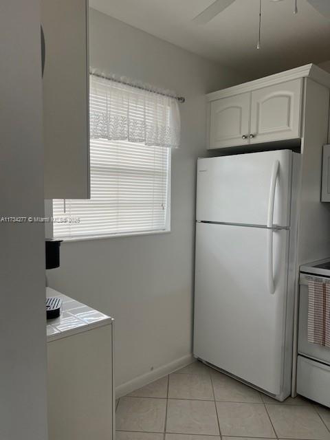 kitchen featuring white cabinetry, light tile patterned floors, white fridge, range with electric cooktop, and ceiling fan