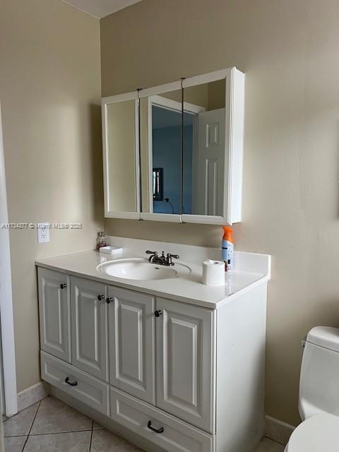 bathroom with tile patterned flooring, vanity, and toilet