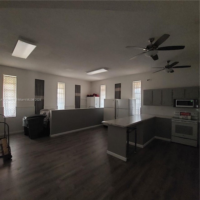 kitchen with white appliances, dark hardwood / wood-style floors, and kitchen peninsula