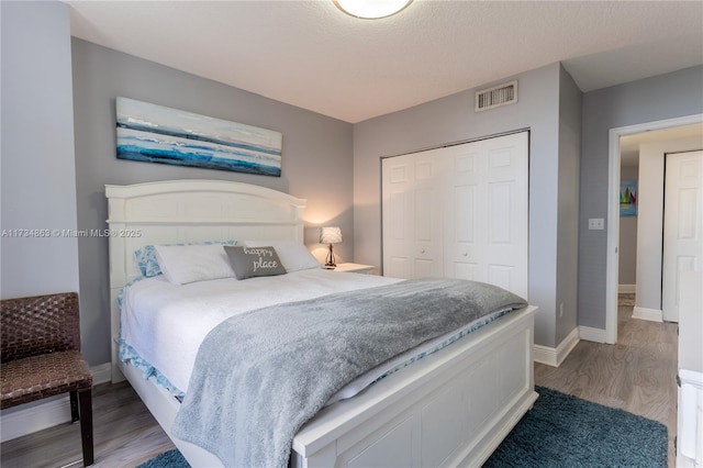 bedroom featuring hardwood / wood-style flooring, a textured ceiling, and a closet