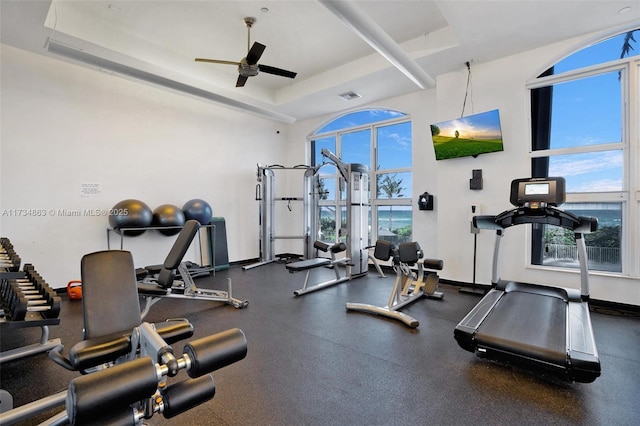 gym featuring ceiling fan and a tray ceiling