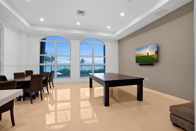 game room with light tile patterned floors and a raised ceiling