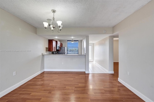 interior space featuring stainless steel appliances, hardwood / wood-style floors, a notable chandelier, and kitchen peninsula