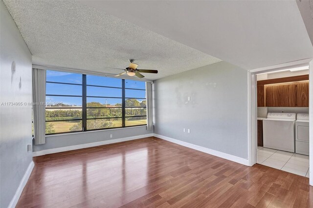 empty room with ceiling fan, washing machine and clothes dryer, a textured ceiling, and light hardwood / wood-style flooring