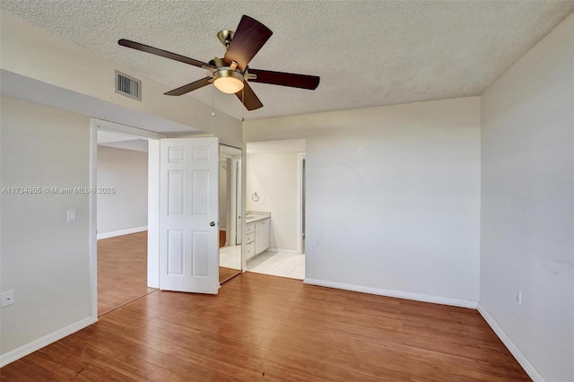 spare room with ceiling fan, a textured ceiling, and light hardwood / wood-style flooring