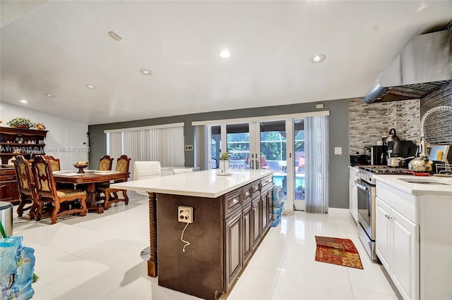 kitchen featuring a breakfast bar, tasteful backsplash, white cabinets, a center island with sink, and french doors