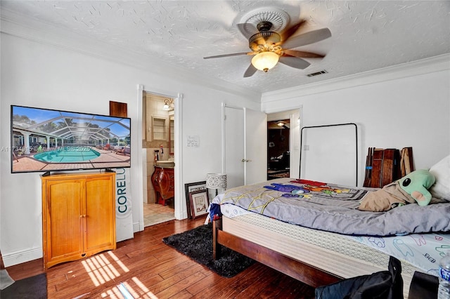 bedroom with ensuite bathroom, hardwood / wood-style floors, ceiling fan, crown molding, and a textured ceiling