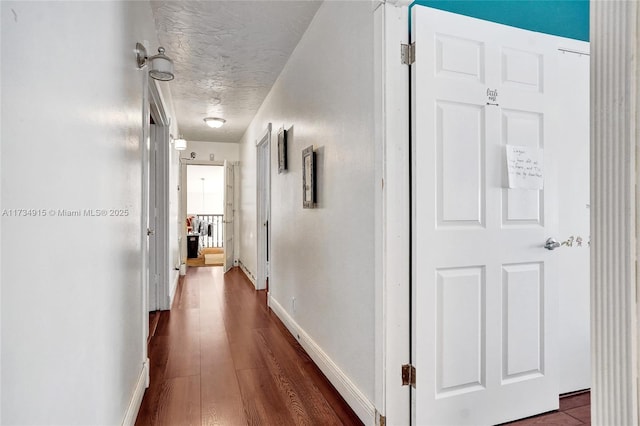 hallway featuring dark wood-type flooring and a textured ceiling