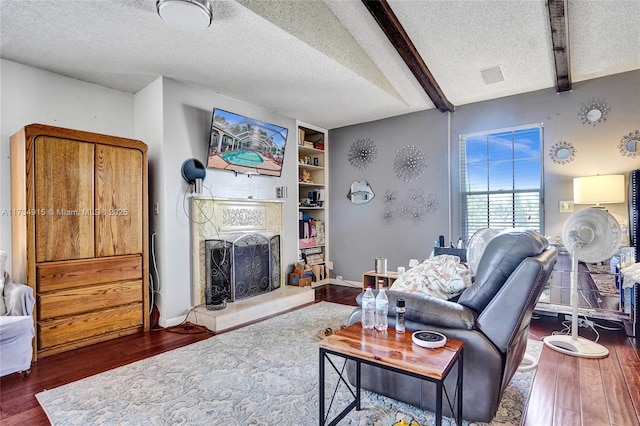 living room featuring beamed ceiling, built in features, dark hardwood / wood-style floors, and a textured ceiling