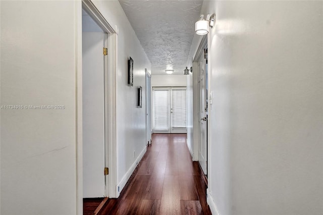 hall with dark hardwood / wood-style floors and a textured ceiling