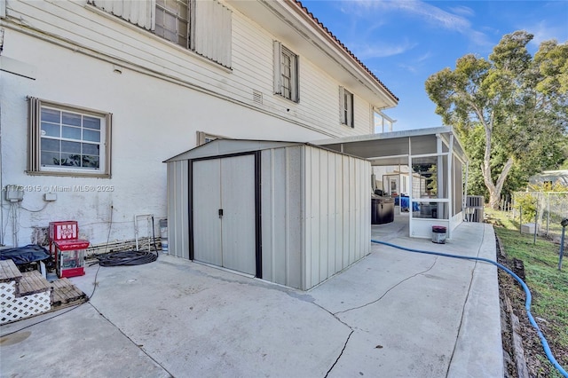 view of patio / terrace with central AC, a sunroom, and a storage unit