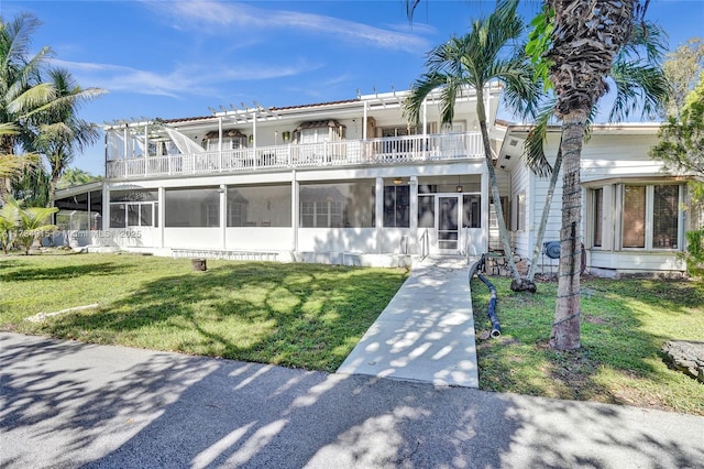 view of front of house featuring a front yard, a sunroom, and a balcony