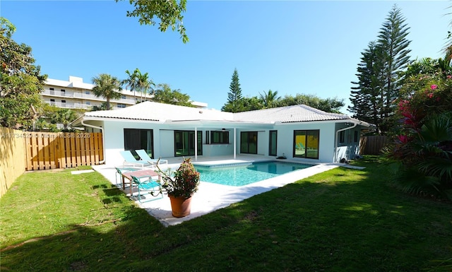 rear view of house featuring a fenced in pool, a lawn, and a patio area