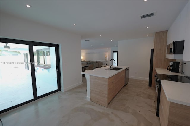 kitchen with light brown cabinetry, sink, range, a center island with sink, and stainless steel dishwasher