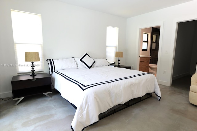 bedroom with concrete floors and ensuite bath