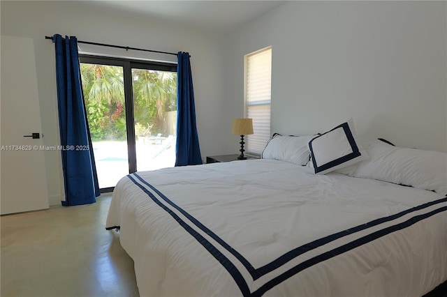 bedroom featuring multiple windows, concrete flooring, and access to exterior