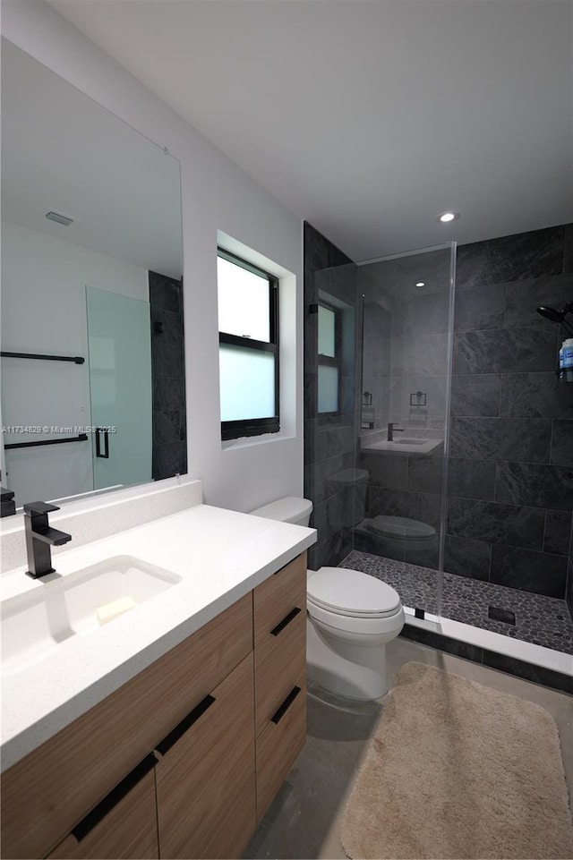 bathroom with vanity, toilet, and tiled shower