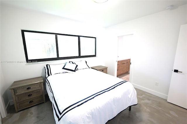 bedroom featuring ensuite bathroom and concrete floors