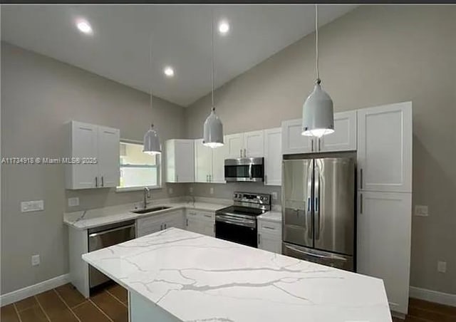 kitchen with appliances with stainless steel finishes, decorative light fixtures, white cabinetry, sink, and light stone counters