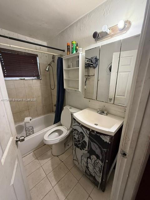 full bathroom with shower / bathtub combination with curtain, vanity, tile patterned flooring, and toilet