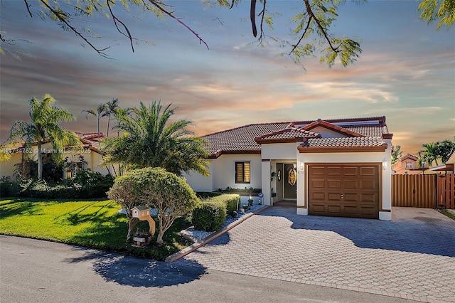 mediterranean / spanish home featuring a garage and a lawn