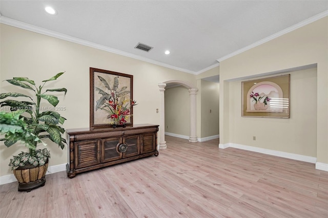 hallway featuring ornamental molding, decorative columns, and light wood-type flooring