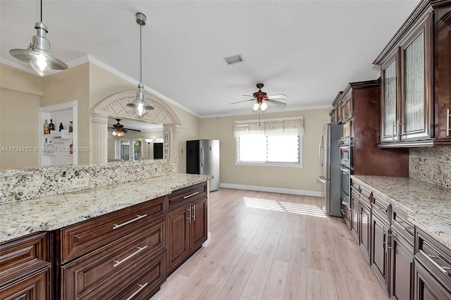 kitchen with dark brown cabinetry, ornamental molding, and stainless steel refrigerator