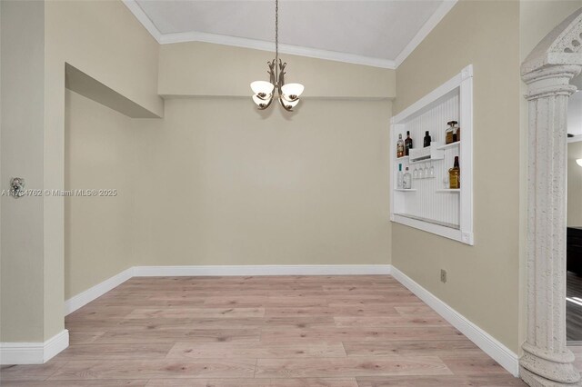 unfurnished dining area with ornate columns, ornamental molding, an inviting chandelier, and light hardwood / wood-style flooring