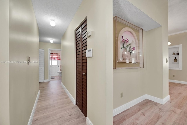 corridor with a textured ceiling and light hardwood / wood-style floors