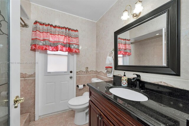 bathroom with tile patterned flooring, vanity, tile walls, and toilet