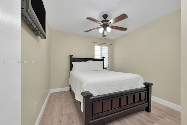 bedroom with ceiling fan, a textured ceiling, and light hardwood / wood-style flooring