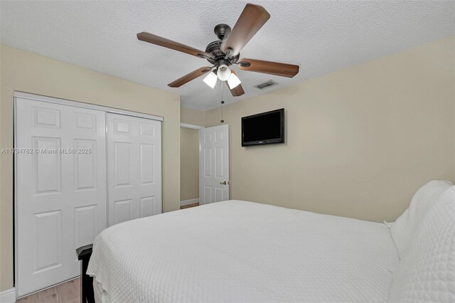 bedroom featuring ceiling fan, light hardwood / wood-style flooring, a textured ceiling, and a closet