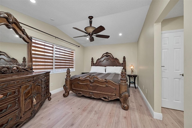 bedroom with ceiling fan, light hardwood / wood-style floors, vaulted ceiling, and a textured ceiling