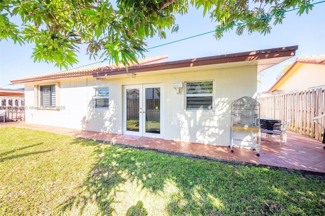 back of property featuring french doors, a patio, and a lawn