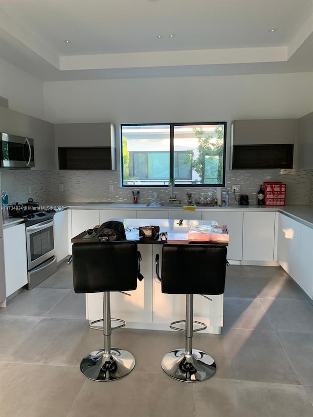 kitchen with stainless steel appliances, white cabinetry, and a breakfast bar area