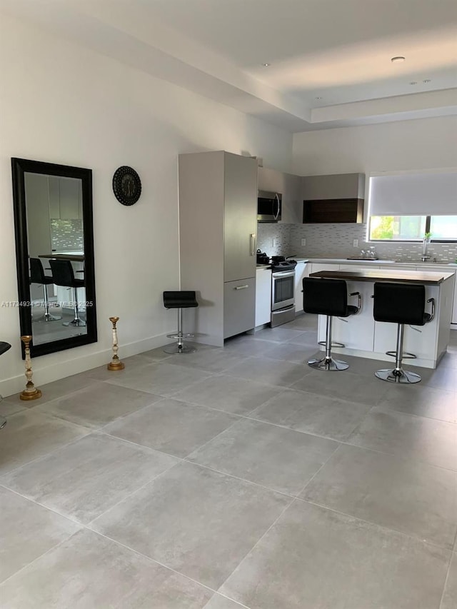 kitchen with sink, a breakfast bar area, tasteful backsplash, appliances with stainless steel finishes, and a kitchen island