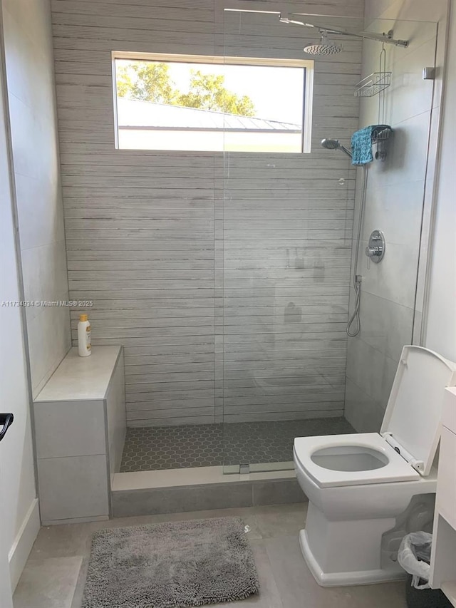 bathroom with a healthy amount of sunlight, toilet, and tiled shower