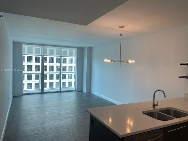 kitchen with dishwashing machine, sink, dark wood-type flooring, expansive windows, and a chandelier