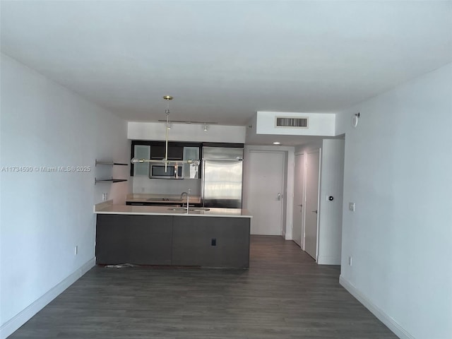 kitchen featuring appliances with stainless steel finishes, dark hardwood / wood-style floors, kitchen peninsula, and sink