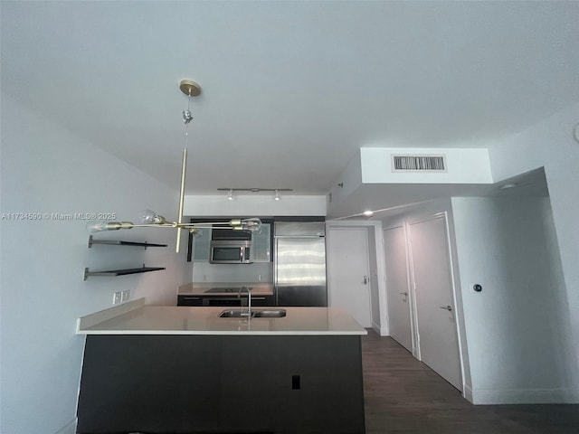 kitchen with sink, dark wood-type flooring, stainless steel appliances, and kitchen peninsula