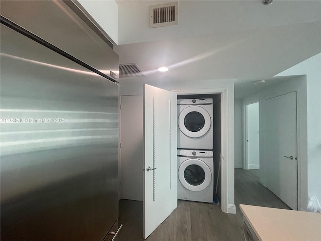 laundry room featuring dark hardwood / wood-style floors and stacked washer / dryer