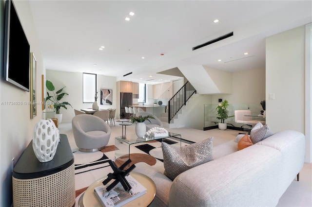 living area with recessed lighting, light carpet, and stairs