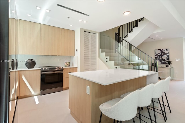 kitchen with electric stove, tasteful backsplash, and a kitchen island