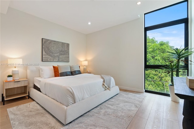 bedroom with expansive windows and hardwood / wood-style floors