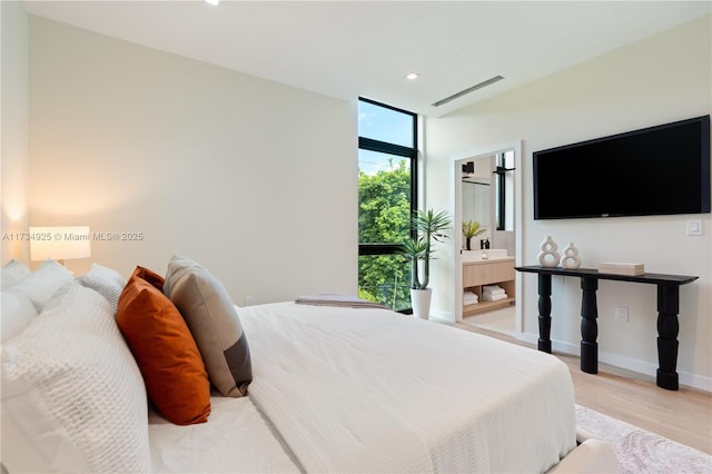 bedroom with a wall of windows and light wood-type flooring