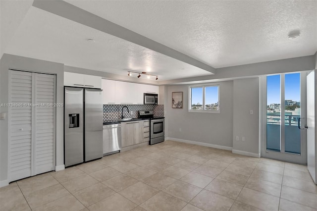 kitchen with white cabinetry, a textured ceiling, light tile patterned floors, stainless steel appliances, and decorative backsplash