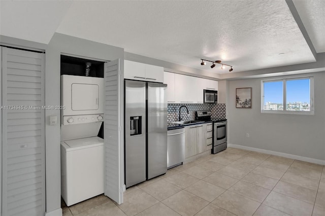 kitchen with white cabinetry, tasteful backsplash, a textured ceiling, stainless steel appliances, and stacked washing maching and dryer