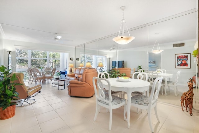 tiled dining space featuring crown molding and ceiling fan