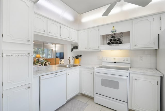 kitchen featuring sink, backsplash, white cabinets, and white appliances