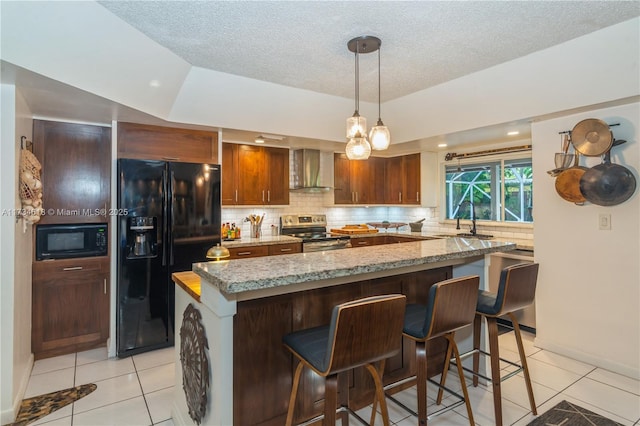 kitchen featuring a kitchen island, wall chimney range hood, light stone counters, and black appliances